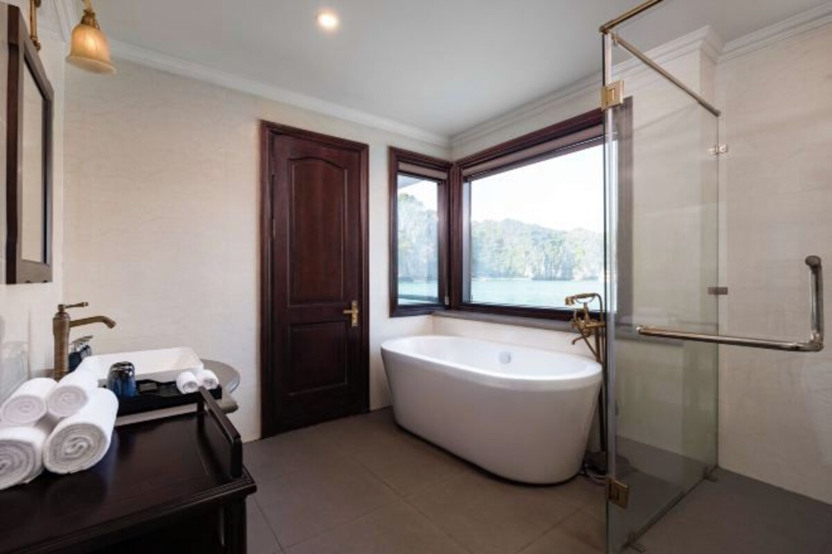 Un baño moderno con una bañera independiente, un box de ducha de vidrio y una ventana con vistas al exterior.