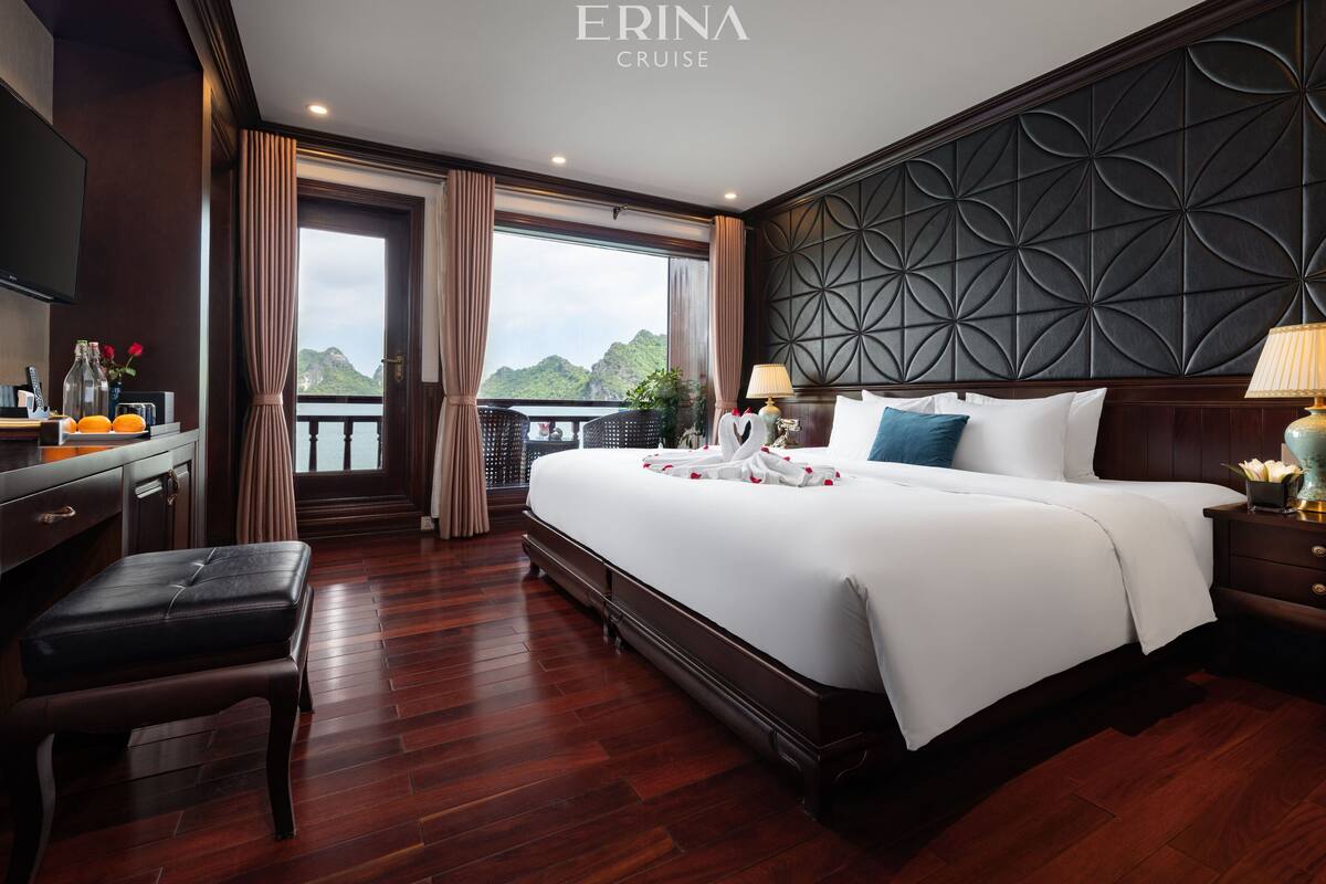 A hotel room with a large bed, a desk, a chair, and a view of the outdoors.