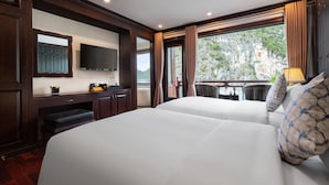 Quarto de hotel com duas camas, televisão, escrivaninha com cadeira e janela com cortinas.