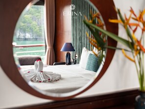 Et hotelværelse med en seng, en lampe, en vase med blomster og udsigt til grønne omgivelser.