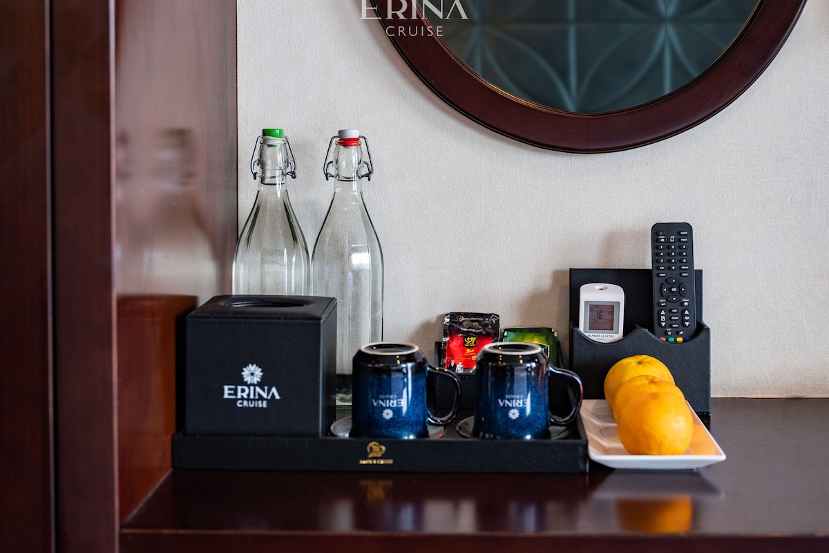 Minibar med vand på flaske, tepakke, fjernbetjening og en skål med frugt.
