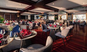 En rummelig restaurant med flere spiseområder, hver med runde borde og stole.