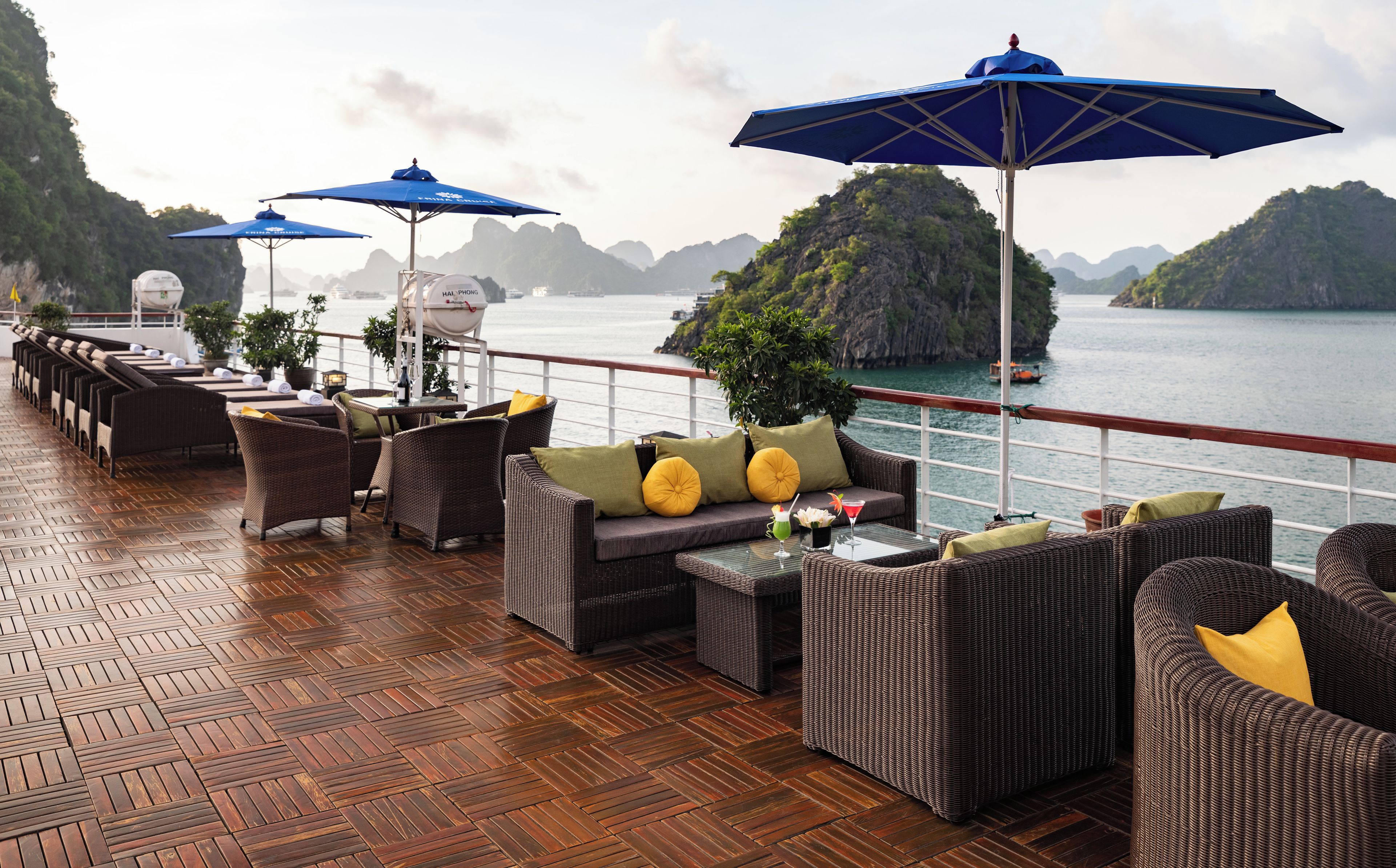 Una terraza con mobiliario de mimbre, sombrillas azules y vistas al mar y a las islas.