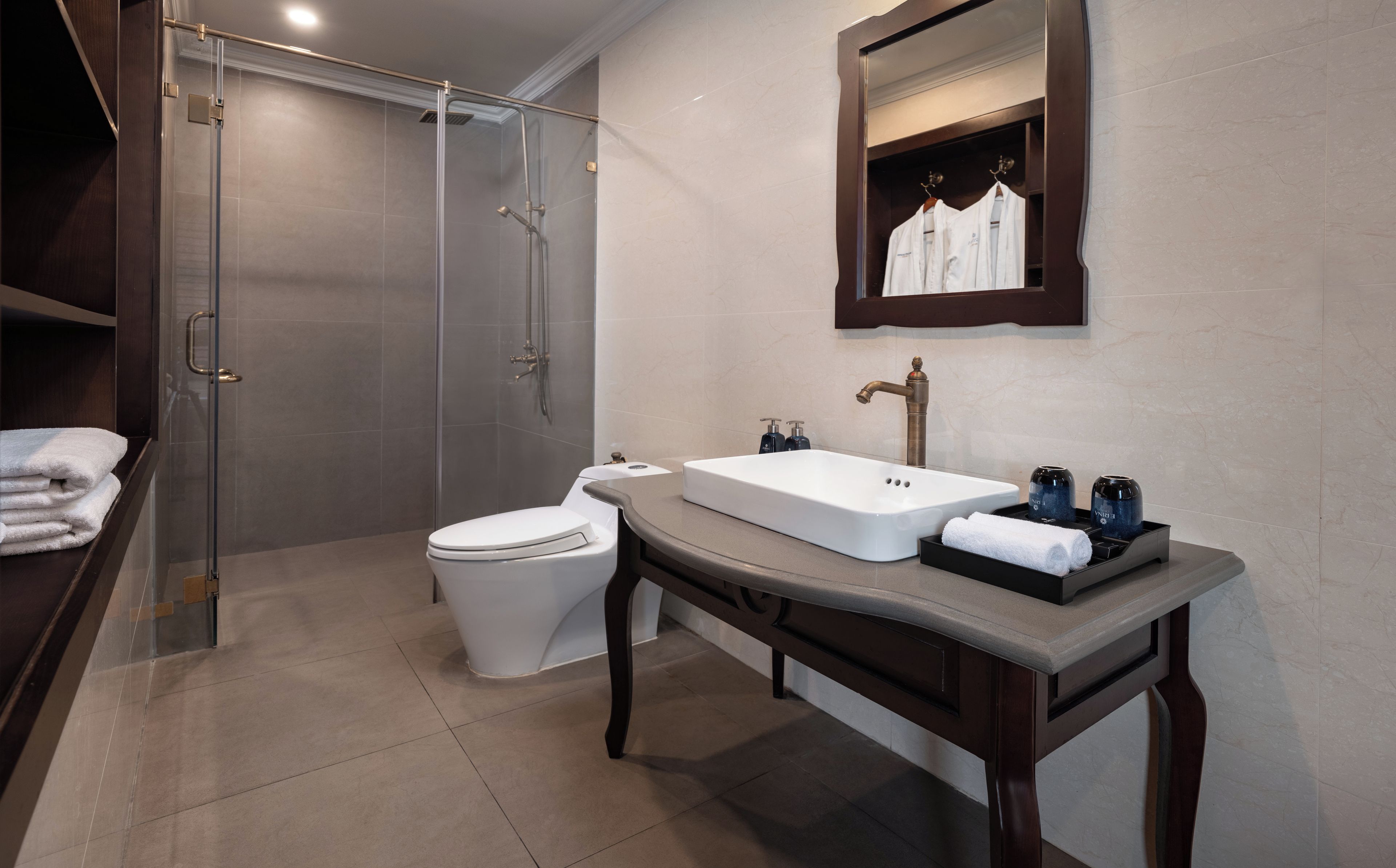A modern bathroom with a glass-enclosed shower, a white toilet, a vanity with a sink, and a mirror above the sink.
