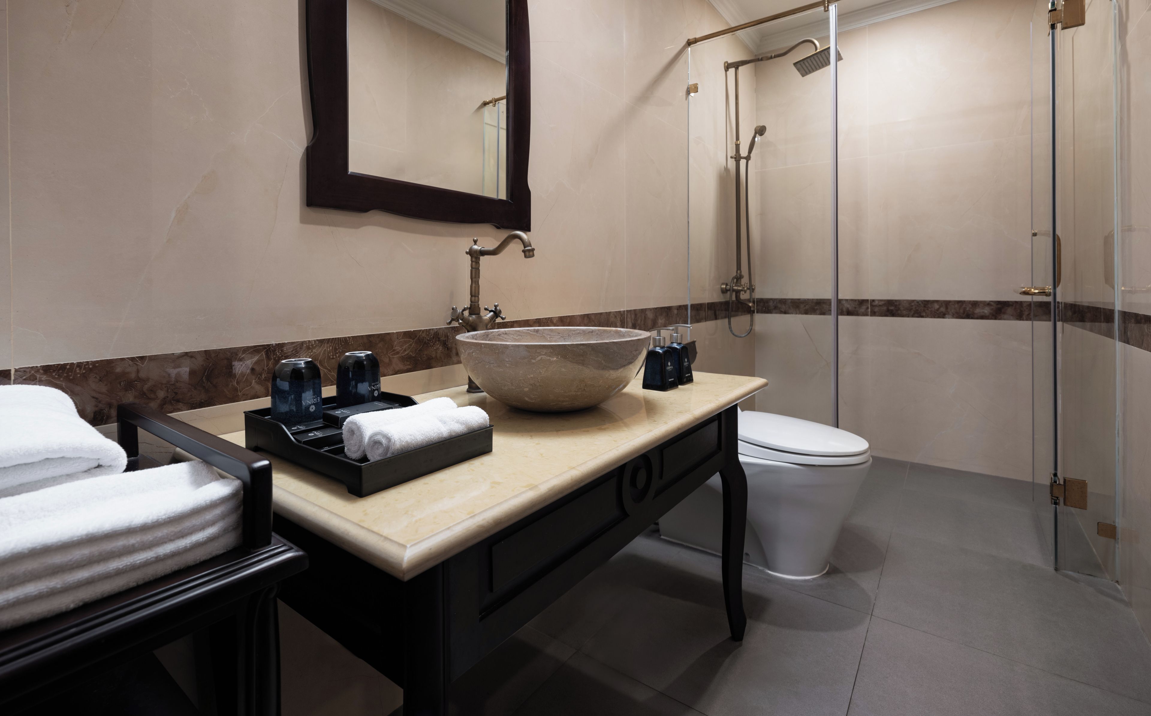 Un baño con un espejo grande, un lavabo, un inodoro y una ducha con mampara de cristal.