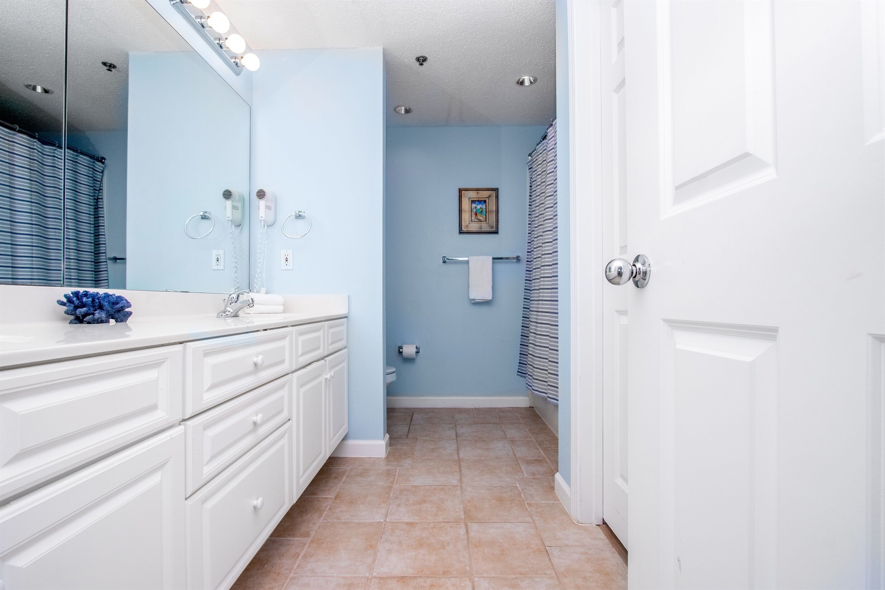 A bathroom with a white vanity, a large mirror, and a towel rack.