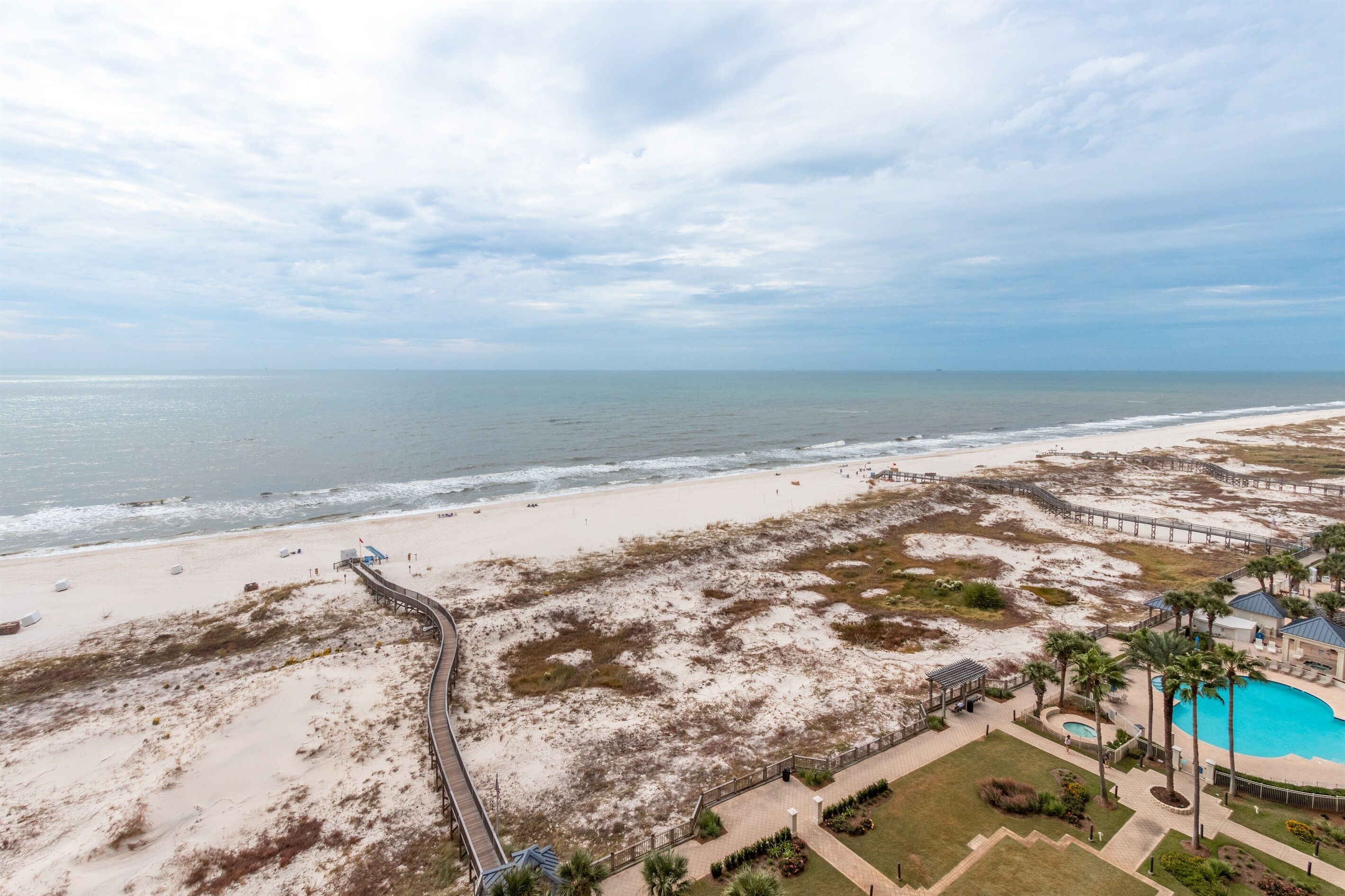 A beach resort with a boardwalk, a swimming pool, and a view of the ocean.