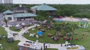 Een park met food trucks, picknickplekken en een gebouw met een groen dak.