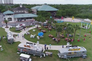 A park with food trucks, outdoor seating, and a building with a green roof.