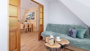 Een gezellige kamer met een houten eettafel, een groene bank en een schilderij aan de muur.
