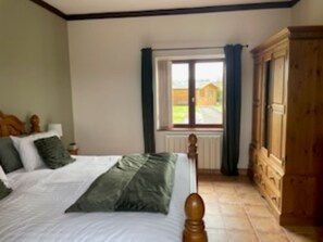 A bedroom with a bed, a window, and a wooden wardrobe.