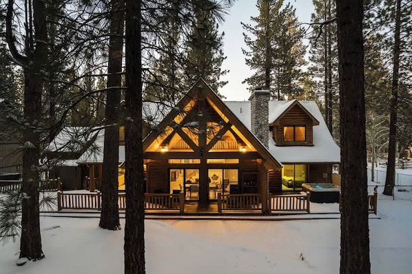 A cabin with a central open area, a hot tub, and a stone chimney.