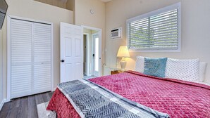Ein Schlafzimmer mit einem Bett, einem Fenster mit Jalousien, einem Deckenventilator und einer Tür.