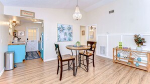 A dining area with a wooden table and chairs, a chandelier, and a decorative console table with plants. - Cozy 1BR Retreat w/ Porch – Near Beaches & Airport (Bradenton)