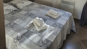 Une chambre à coucher comprenant un lit, une table de chevet, une lampe, une fenêtre avec des rideaux et un tableau décoratif au mur.