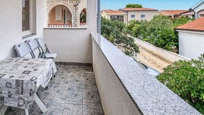 A balcony with a table and chairs, a stone floor, and a view of neighboring houses. - Beach front apartment in Vir with WiFi (Vir)