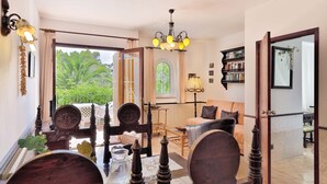 A dining area with a table set for four, a chandelier, and a view of the outdoors. - 2-Bedroom Holiday Apartment with Beach Access in Cala D'Or (Santanyí)