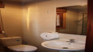 A small bathroom with a toilet, sink, and mirror. - Hostal Cervantes (Daganzo de Arriba)