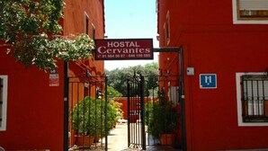 A red building with a sign for 'Hostal Cervantes' and a gate. - Hostal Cervantes (Daganzo de Arriba)