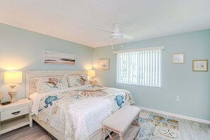 A bedroom with a bed, bedside tables, a ceiling fan, and a window with blinds.