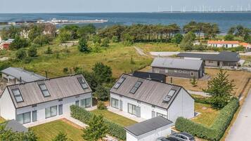 Ett bostadsområde med moderna hus, fri utsikt över havet och vindkraftverk i fjärran.