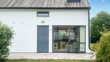 Ett modernt hus med en stor skjutdörr av glas, ett litet fönster och ett tydligt synligt nummer, ”50”, på dörren.