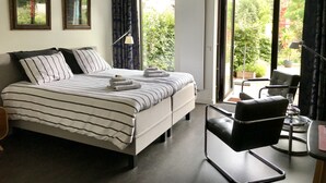 Habitación de hotel con cama, una silla, un escritorio y vistas a zonas verdes.