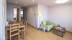A room with a wooden dining table, chairs, a green sofa, a small coffee table, and a floor lamp. - HOME Tengachaya3F (Osaka)