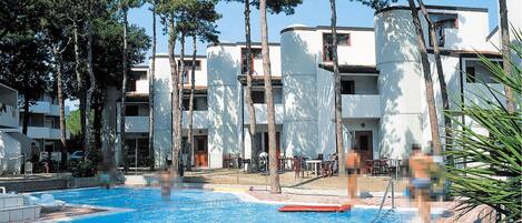 Une piscine entourée d’arbres et de bâtiments modernes dotés de balcons.