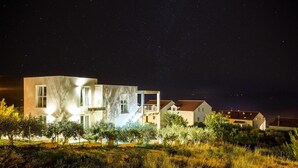 Uma casa moderna com varanda e jardim à noite.