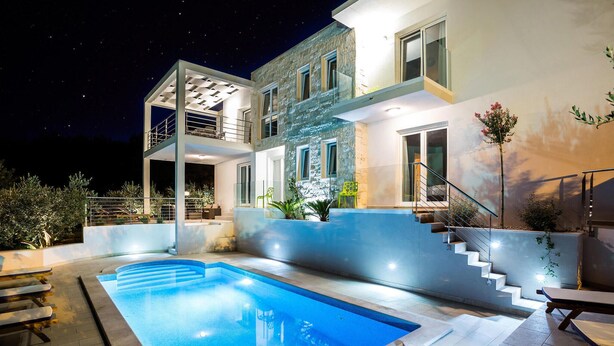Uma casa moderna de dois andares com piscina, área de estar externa e escadaria que leva ao andar superior.