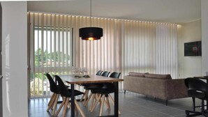 Un comedor moderno con mesa y sillas de madera, un sofá y una lámpara colgante.