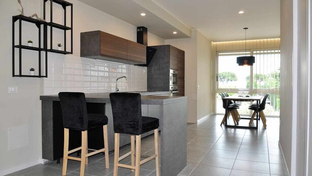 Una cocina moderna con una isla central, taburetes de bar y un comedor con mesa y sillas.