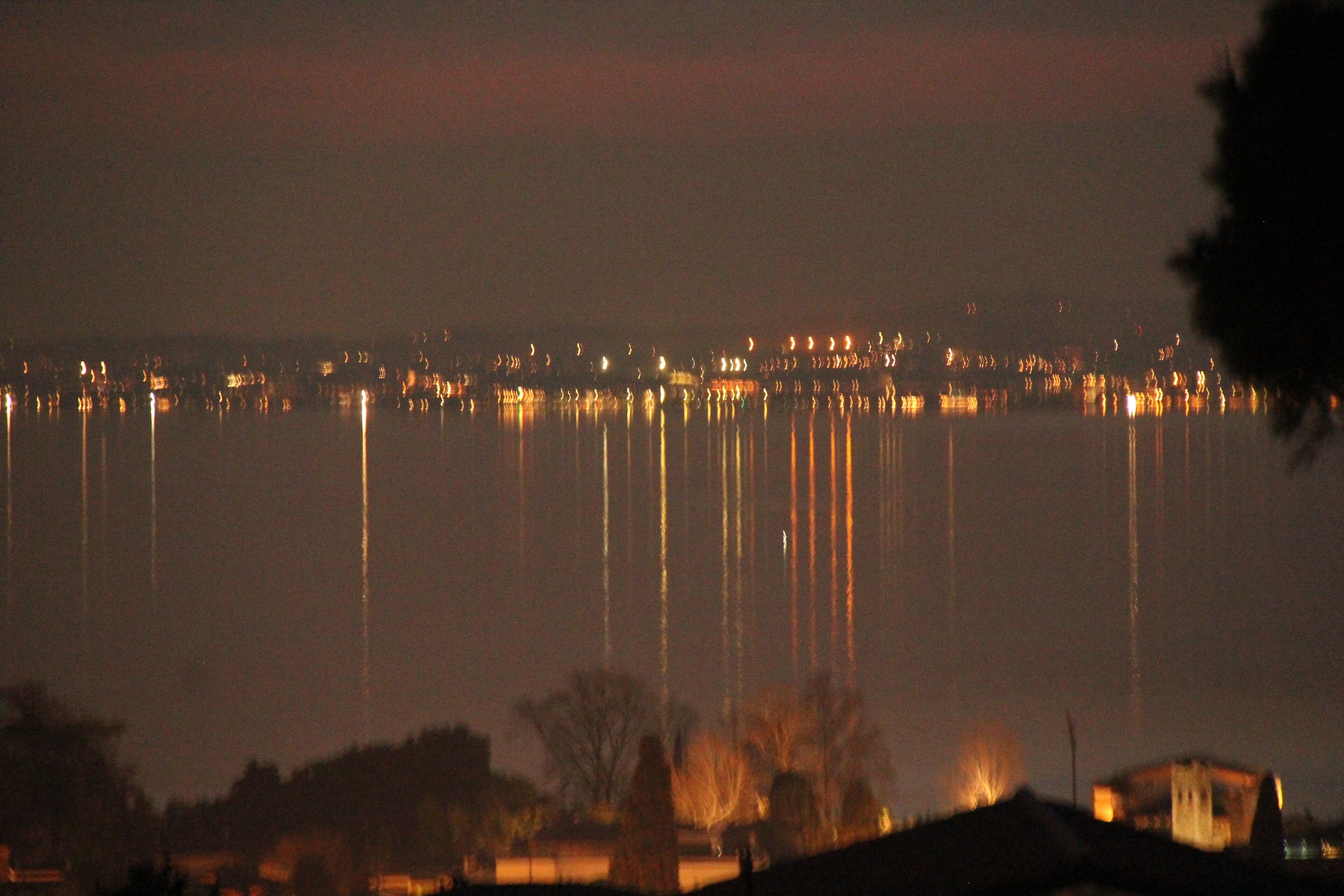 A nighttime view of a waterfront with buildings and trees.