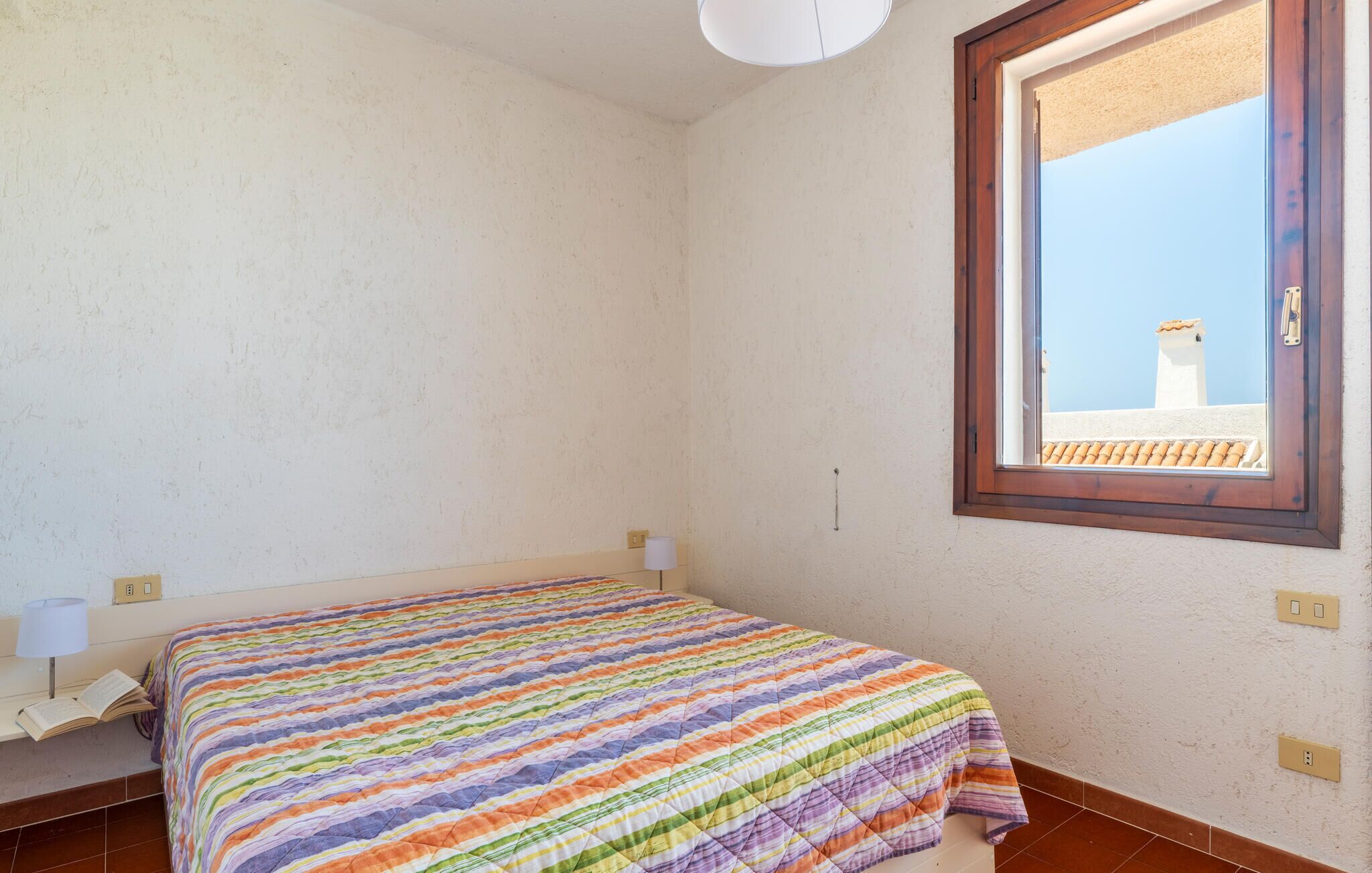 Une chambre à coucher avec un lit, une fenêtre et une vue sur un immeuble.