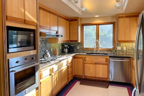 Enjoy cooking in this well-equipped kitchen with a range, microwave, and gas stove, complemented by cabinetry and a window with a view.