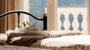 Un lit donnant sur un balcon et les montagnes, vu à travers une fenêtre.