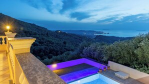 Une piscine à débordement située sur le toit, offrant une vue sur la mer et les collines.