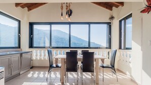 Une cuisine dotée d’une grande fenêtre, une table à manger avec des chaises, et une vue sur les montagnes.