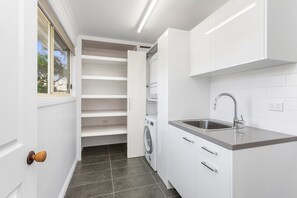 Una cocina compacta con lavadora integrada, un lavabo y un ventanal.