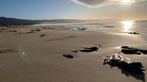 A beach with a clear sky, calm sea, and distant mountains. - Ocean's 8 (Marengo)