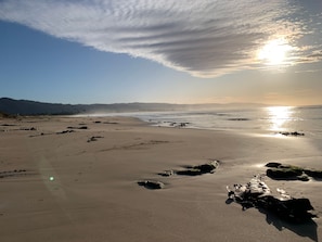 A beach with a clear sky, calm sea, and distant mountains. - Ocean's 8 (Marengo)