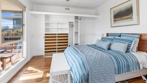 Un dormitorio con cama, ventilador de techo, ventana grande y un cuadro en la pared.
