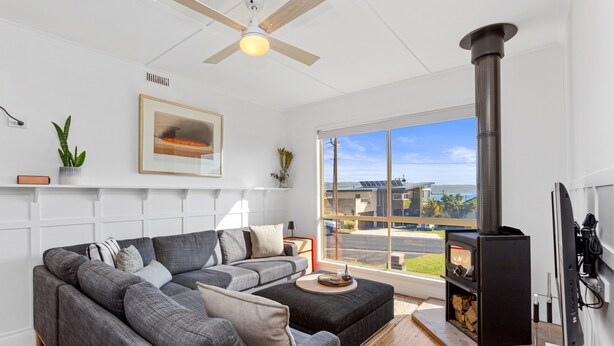 Una sala de estar moderna con un sofá seccional gris, una chimenea y un ventanal con vistas al exterior.