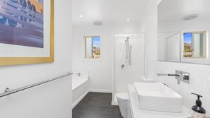 Een moderne badkamer met douche, toilet en wastafel.
