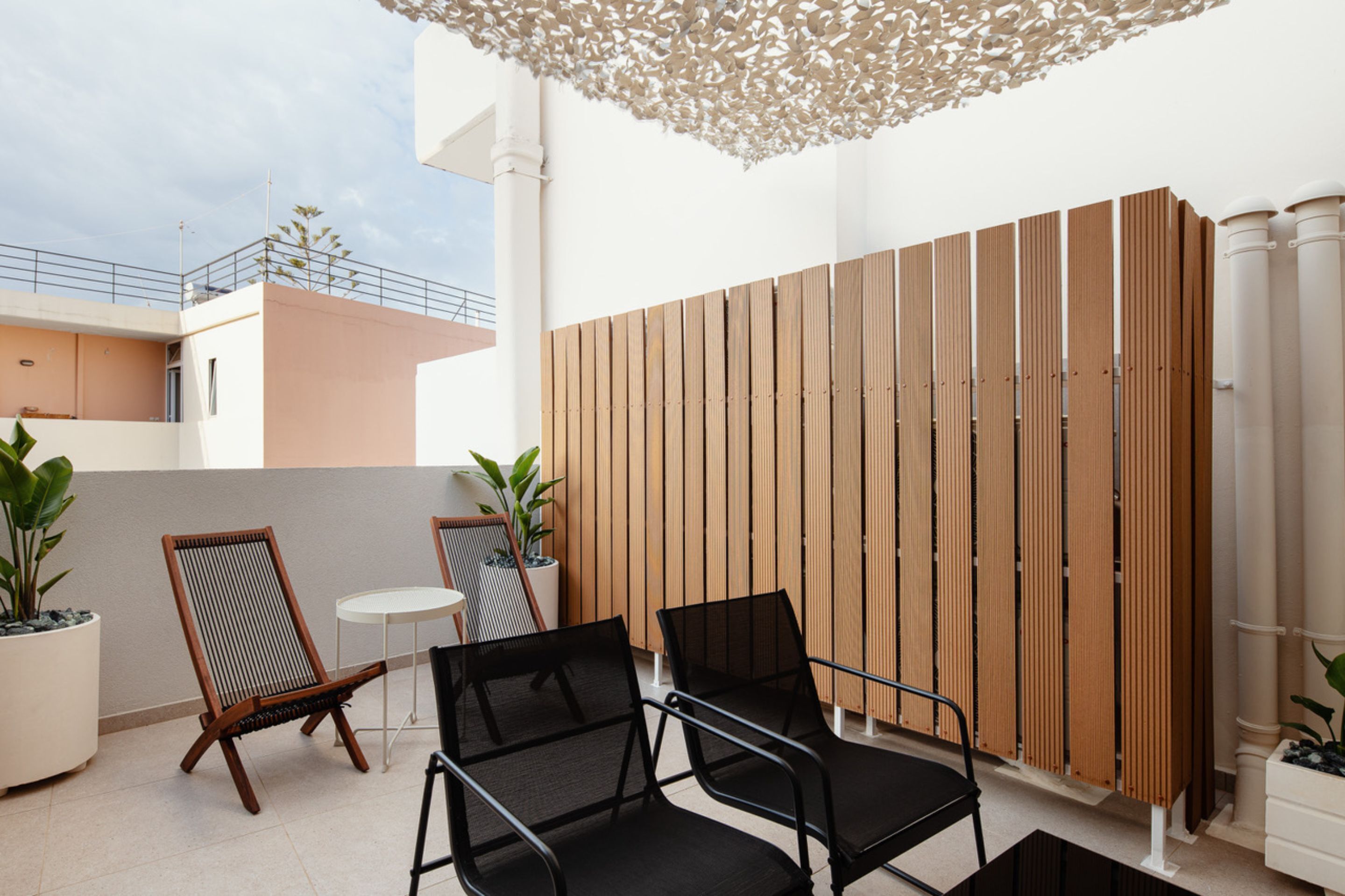 Un espace patio comprenant deux chaises en bois, une petite table ronde et une clôture décorative en bois.