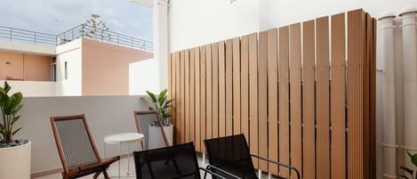 Un espace patio comprenant deux chaises en bois, une petite table ronde et une clôture décorative en bois.