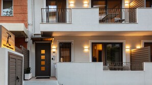 Un edificio moderno con una puerta de entrada oscura, varias ventanas y un balcón con barandillas metálicas.