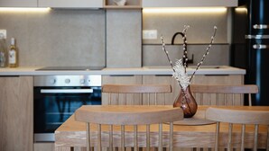Una cocina moderna con armarios de madera, horno empotrado y comedor con mesa y sillas de madera.