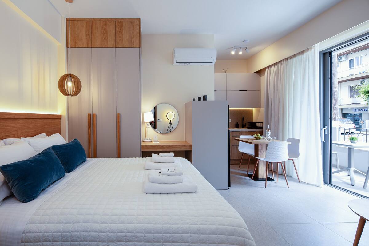 A modern hotel room with a large bed, a desk, and a dining area.